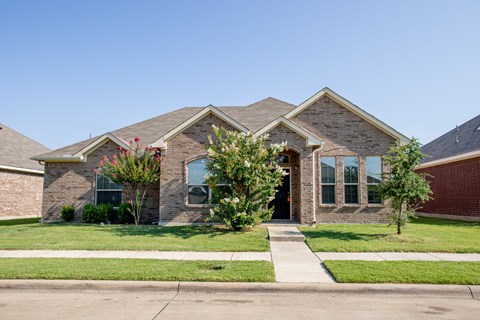 a brick house with a sidewalk in front of it