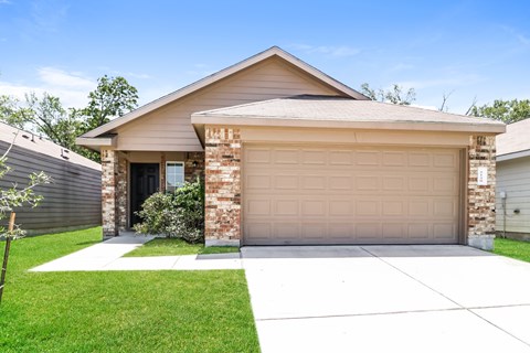 a tan house with a garage door and a lawn