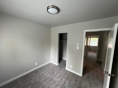 a living room with gray carpet and a door to a hallway