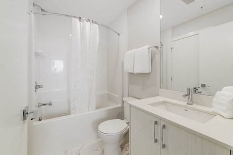 A white bathroom with a toilet, sink, and shower.