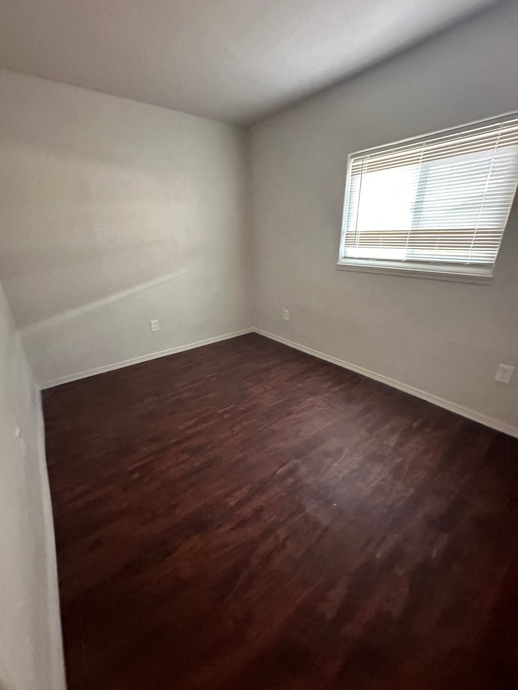 an empty room with wooden floors and a window