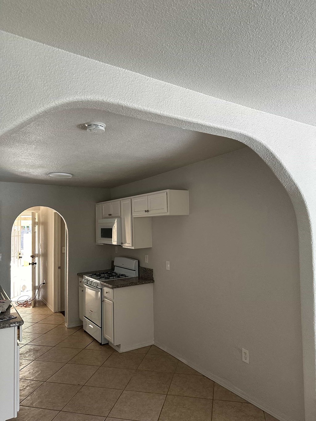 a kitchen with an archway and a stove and cabinets