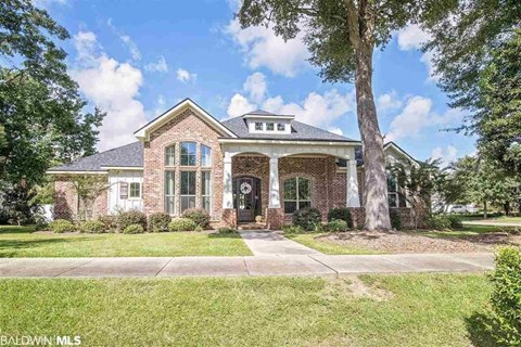 A house with a front yard and a tree in front of it.