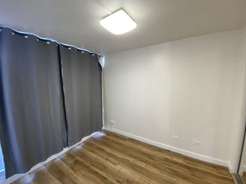 A room with wooden flooring and a window with grey curtains.
