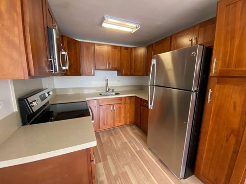 A kitchen with wooden cabinets and a stainless steel refrigerator.