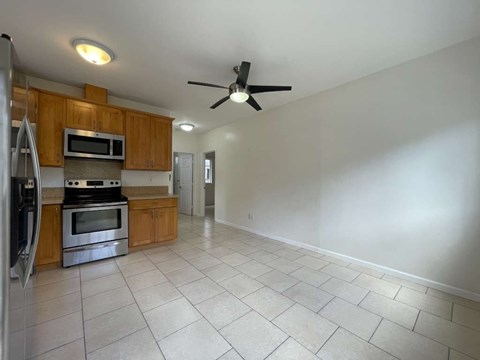A kitchen with a refrigerator, microwave, oven, and a ceiling fan.