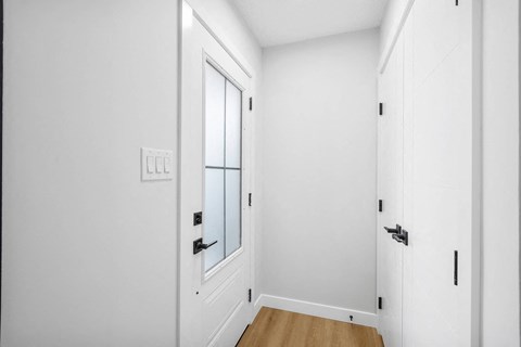 a bedroom with white walls and a door with a window