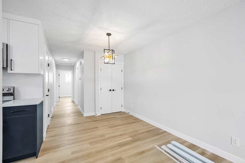 a renovated kitchen and hallway with white cabinets and wood floors