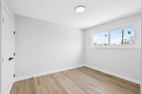 an empty bedroom with white walls and a window