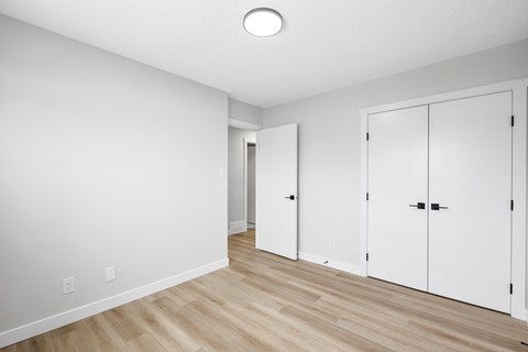 an empty room with white closets and a wood floor