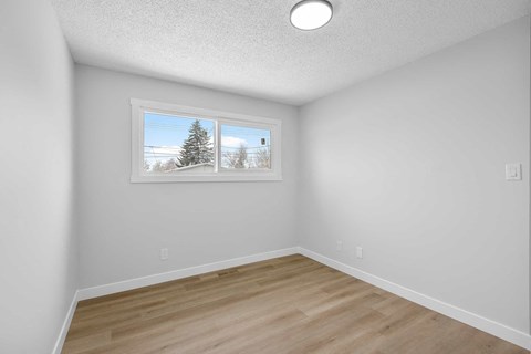 an empty room with hardwood floors and a window