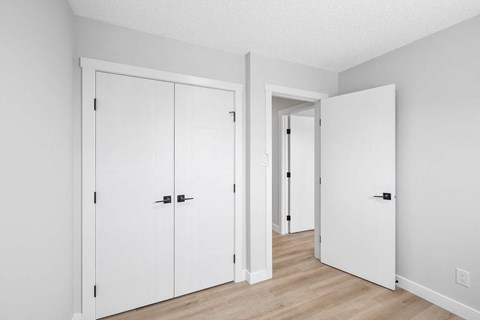 an empty room with white closets and a wood floor