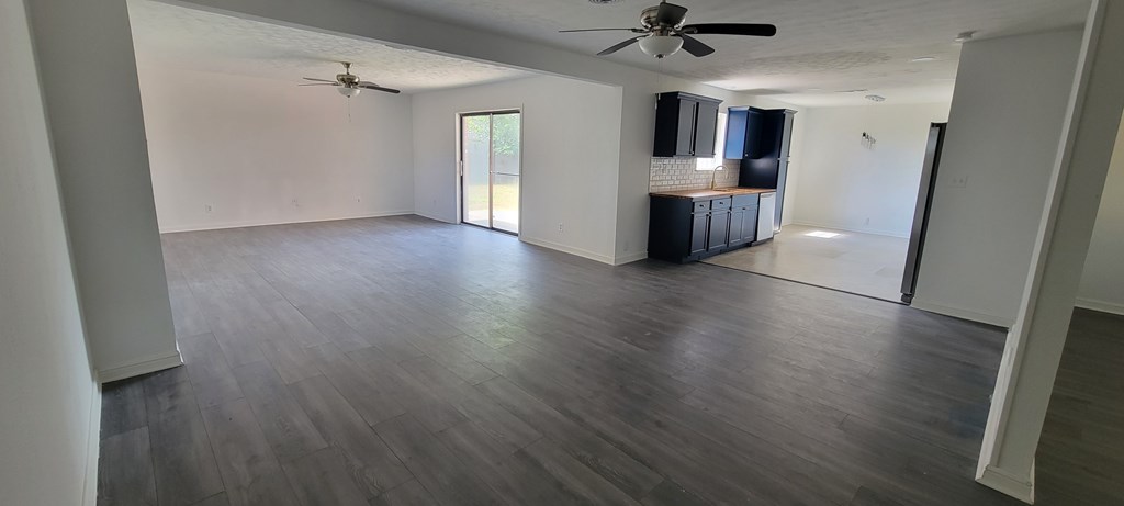 A spacious room with a ceiling fan and a door leading to another room.