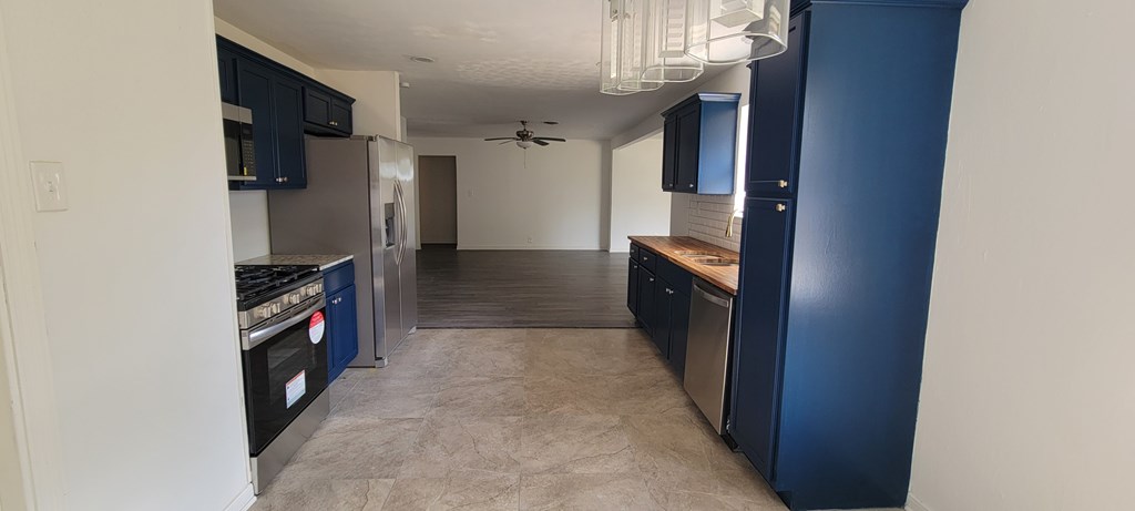 A kitchen with blue cabinets and a stainless steel refrigerator.