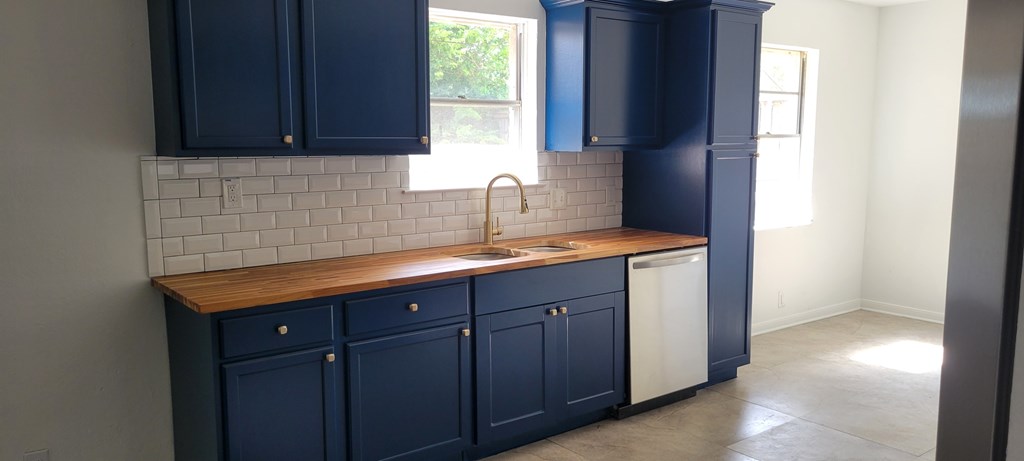 A kitchen with dark blue cabinets and a wooden countertop.