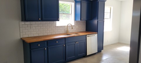 A kitchen with dark blue cabinets and a wooden countertop.