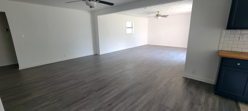 A room with a ceiling fan and wooden flooring.