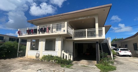 A two-story house with a balcony and a car parked in the driveway.