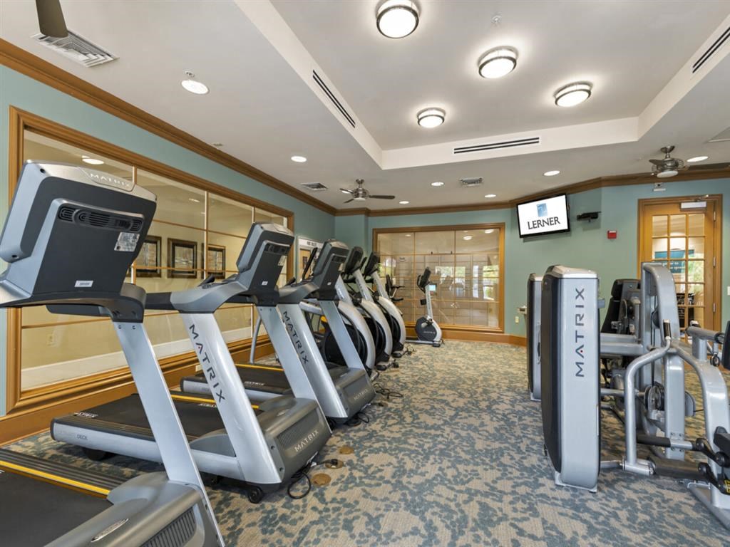 a gym with cardio equipment and a wall mounted tv