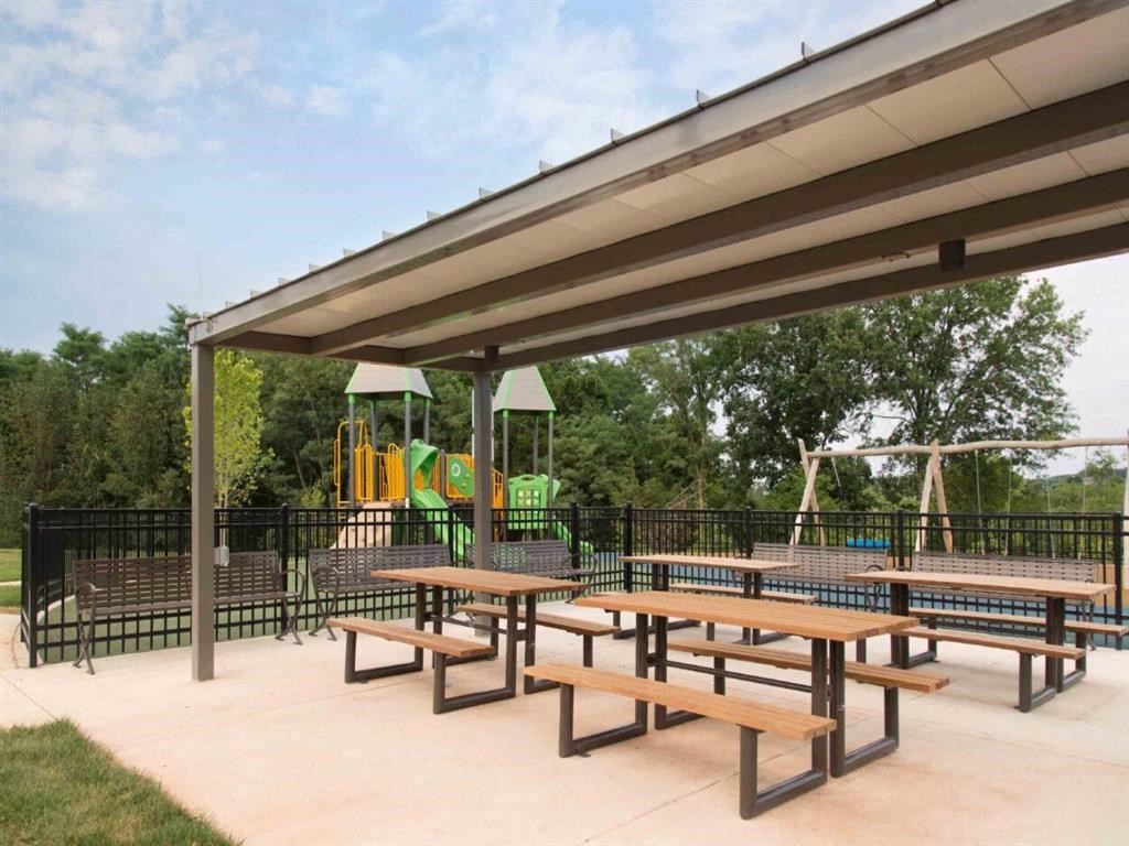a picnic area with benches and a playground in the background