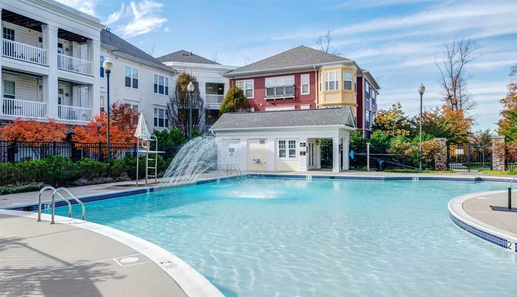 a large pool with a fountain in front of an apartment building