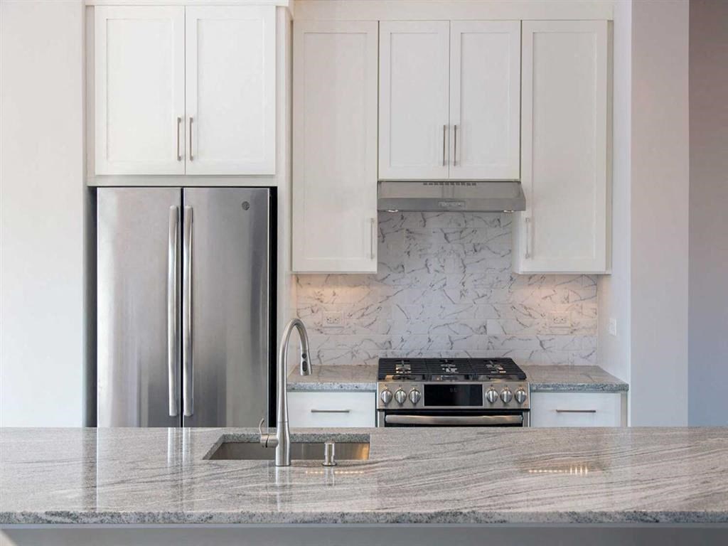 a kitchen with white cabinets and a stainless steel refrigerator