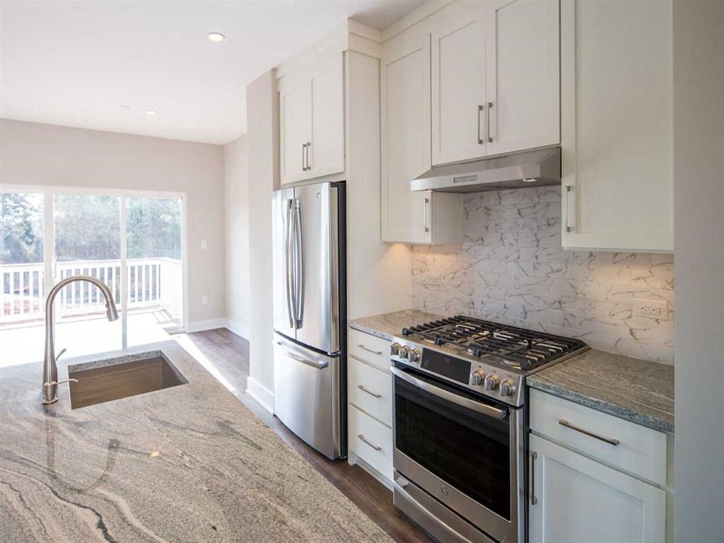 a white kitchen with stainless steel appliances and a sink