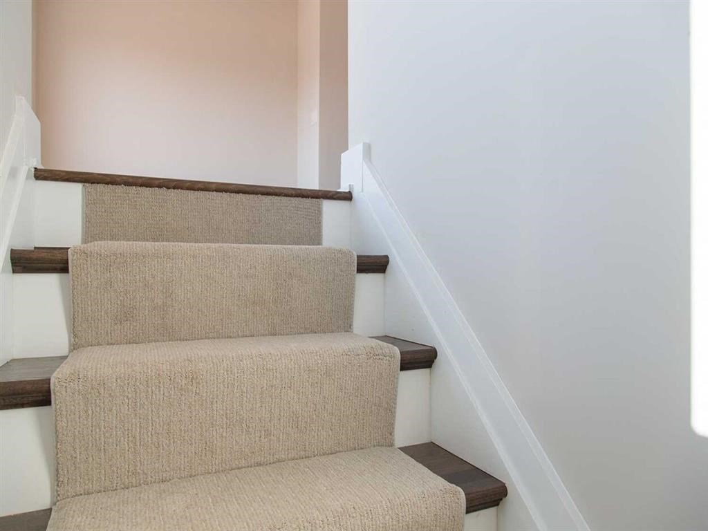 stairs in a home with white walls and carpeting