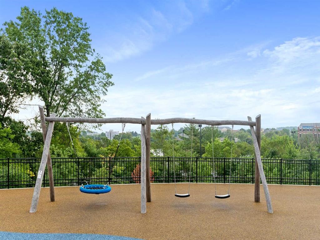 a swing set with a fence and trees in the background