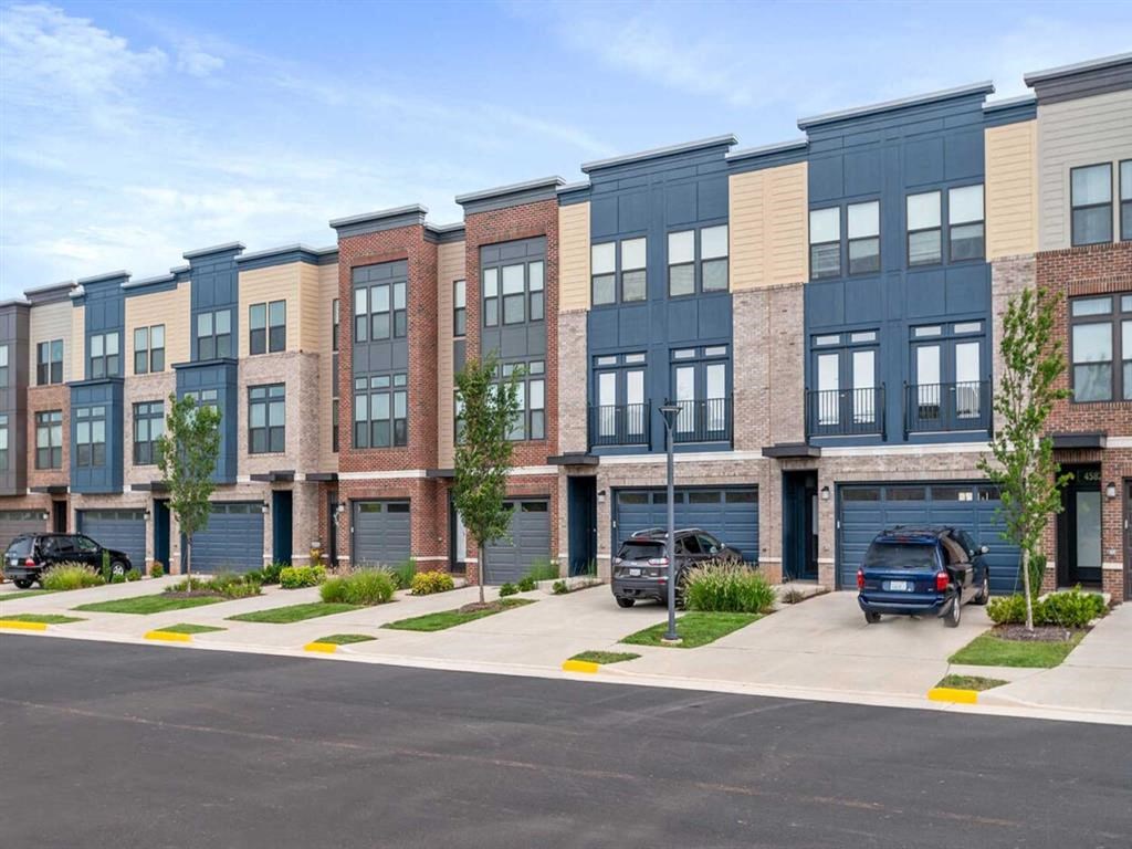 a row of new apartment buildings with cars parked in a parking lot