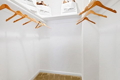 a walk in closet with shoe racks and bags on the wall