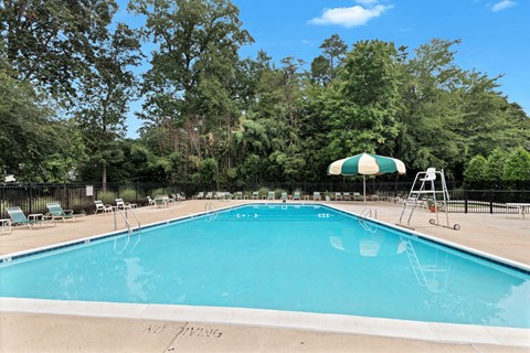 a swimming pool with a green and white umbrella and chairs around it
