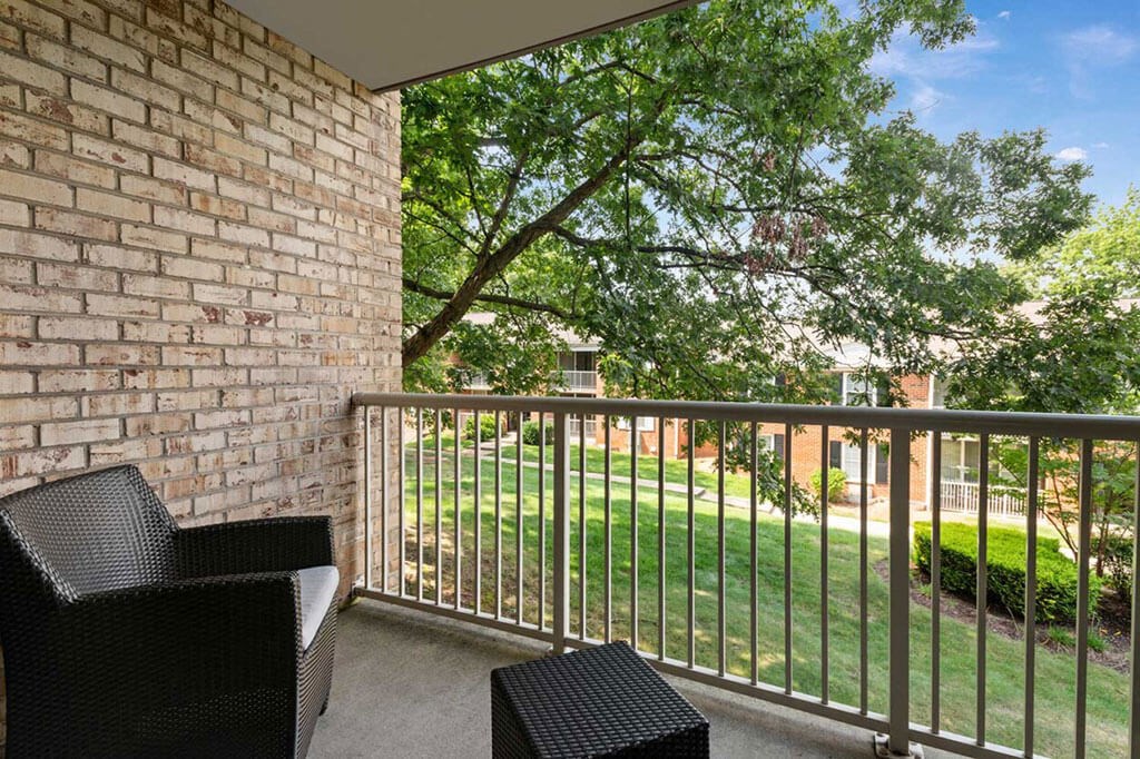 a balcony with two chairs and a tree in the yard