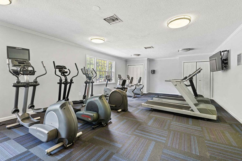 a gym with various exercise machines and a tv