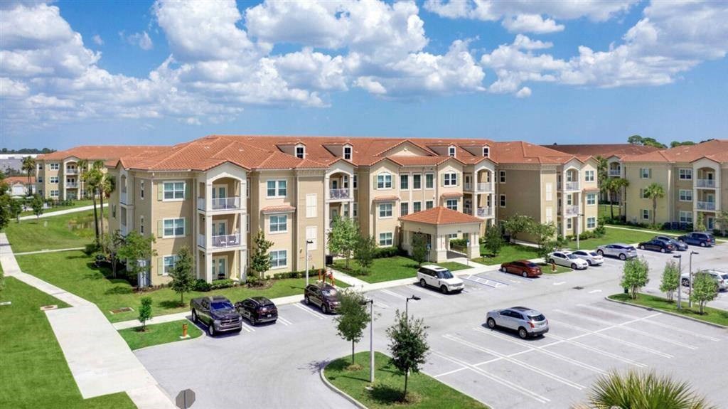 an image of an apartment complex with cars parked in a parking lot