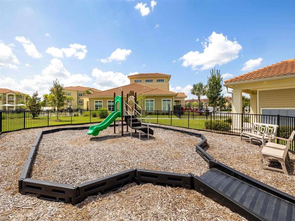 a playground with a slide and chairs in front of a house