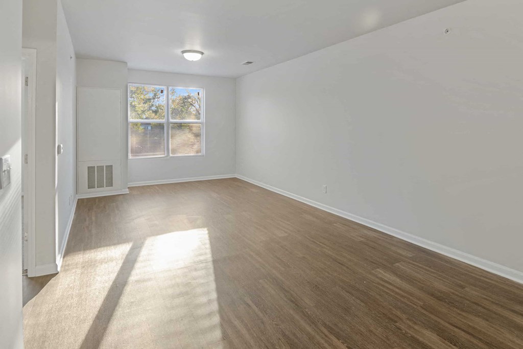 A room with wooden flooring and a window with a view of trees outside.