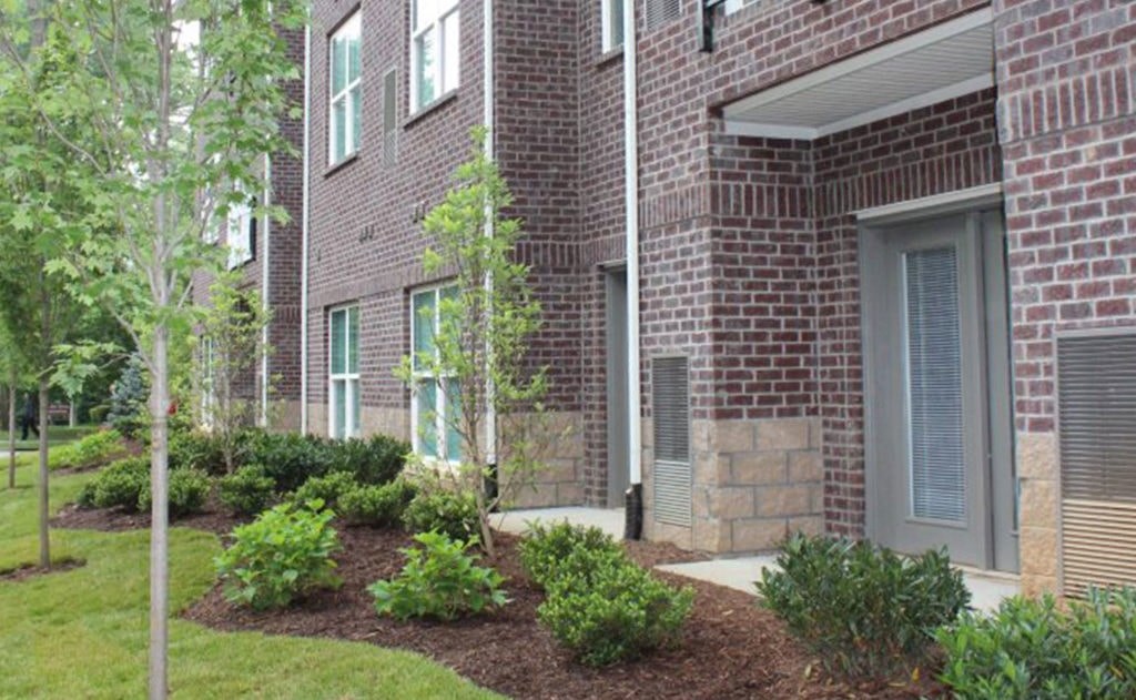 A red brick building with a tree in front.