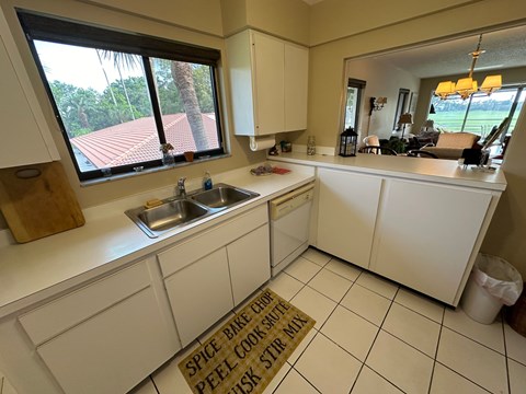 a kitchen with white cabinets and a sink and a window
