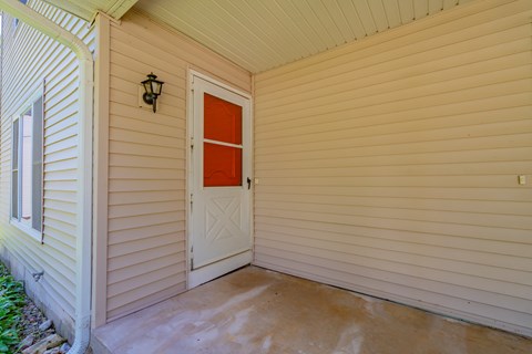 A white door with a red panel is on a beige house.