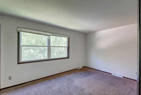 A room with a window and carpeted floor.