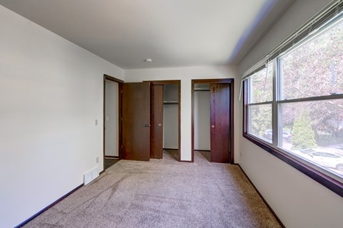 A room with a carpeted floor and a window overlooking a parking lot.