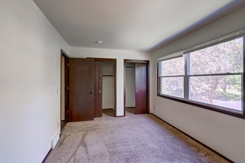 A room with a carpeted floor and two doors.
