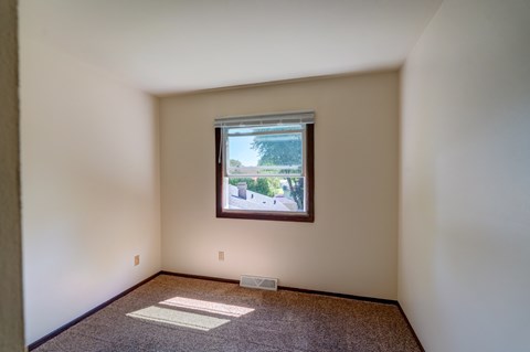 A room with a window and a rug on the floor.