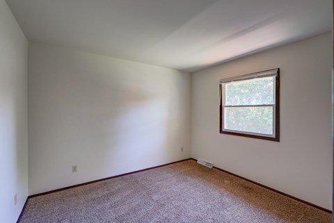 A room with a window and carpeted floor.