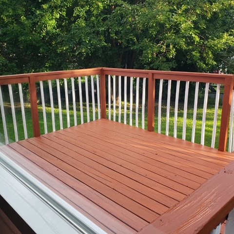 A wooden deck with white railings and a green lawn in the background.