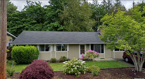 A house with a grey roof and a red car parked in the driveway.