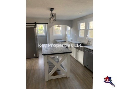 A kitchen with a table in the middle and a logo of Key Properties LLC.