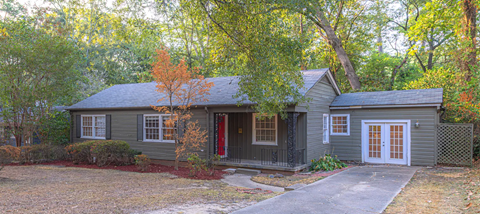 a small gray house with a front yard and trees