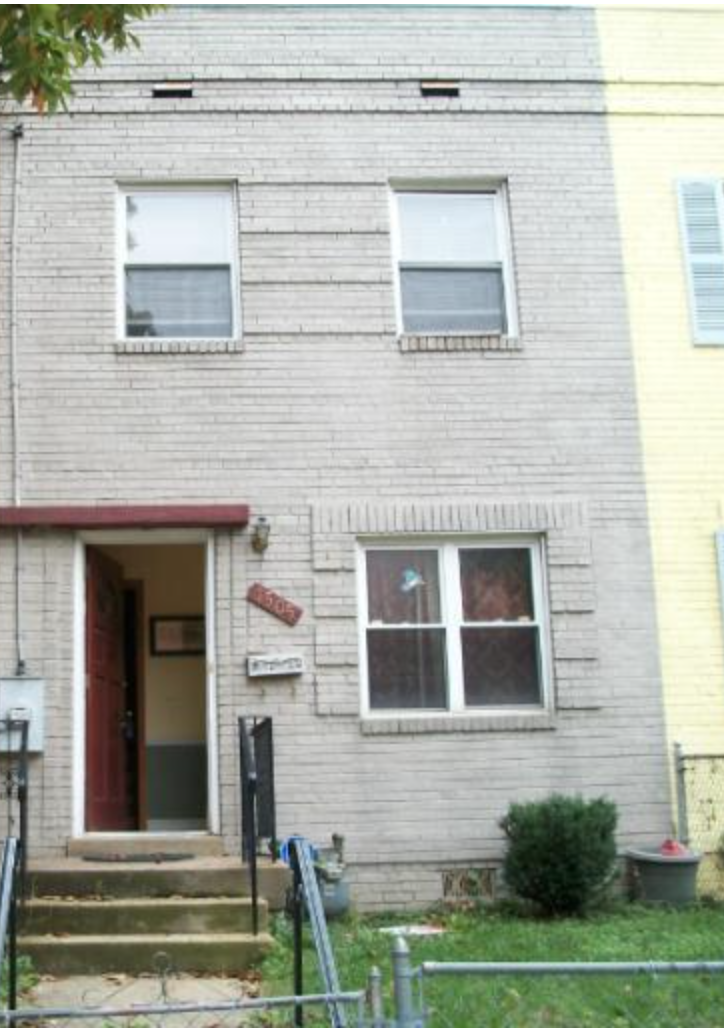 a white brick house with two windows and steps